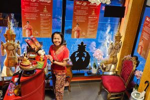 Blick von oben auf den Eingangsbereich von Thai Life Massage Velbert, mit Darunee Goldammer an der Kasse vor dem Schaufenster, das einen einladenden ersten Eindruck des Geschäfts vermittelt.