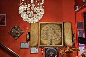 Elegante goldene Wanddekoration in Thai Life Massage Velbert, geschmückt mit gerahmten Zertifikaten von renommierten Massageschulen, die die Inhaberin erfolgreich absolviert hat.