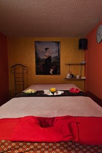 Gemütliche Massage-Liege im stilvoll dekorierten Raum von Thai Life Massage Velbert, mit Lotusblumen als Teil der beruhigenden Deko.