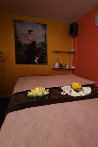 Massage-Liege aus einem anderen Blickwinkel im stilvoll dekorierten Raum von Thai Life Massage Velbert, umgeben von Lotusblumen und einer beruhigenden Atmosphäre.